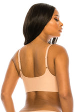 Laser cut beige bralette with smooth, minimalist design showcasing model's flawless skin tone against a plain white background.