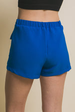 Vibrant blue cargo shorts with functional pockets, showcased on a female model against a plain background.