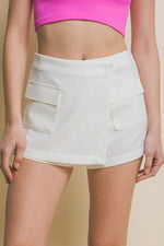 White skorts with cargo pockets, worn by a person in a pink crop top, showcasing the stylish and functional design.