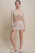 Stylish beige shorts with cargo pockets, paired with a lace-trimmed crop top, showcased on a model with a confident pose.