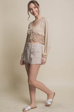 Stylish beige shorts with cargo pockets, paired with a lace-trimmed top, showcasing a feminine yet versatile summer look.