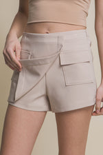 Stylish beige cargo skorts with functional pockets, featured in the Cecelia clothing store. This versatile women's activewear piece offers both comfort and a fashionable look.