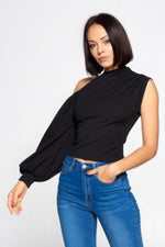 Sleek black one-shoulder top with voluminous puff sleeve, styled with high-waisted jeans for a contemporary fashion-forward look.