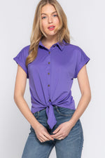 Stylish short sleeve stretch top in vibrant purple, with a front tie detail, showcased on a young woman with blonde hair.