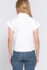 Relaxed white short-sleeved top with front tie detail, modeled by a young blond woman against a plain background.