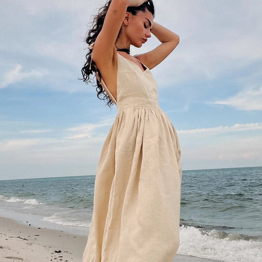 Elegant beach-style vintage loose A-line sling long dress by Cecelia, with the model posing on a sandy shore against a serene ocean backdrop.